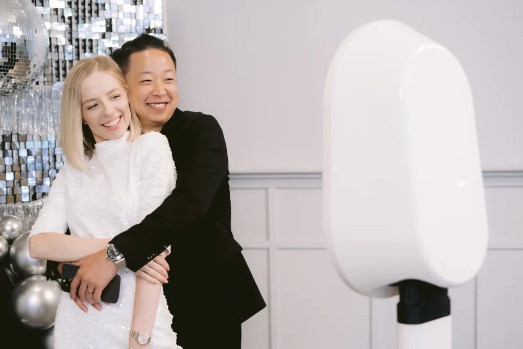 Couple laughing next to the AIRi photo booth at a holiday party