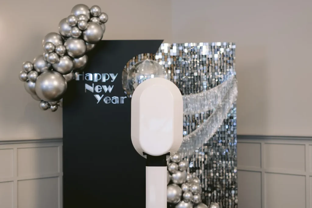 AIRi photo booth beside silver balloons and a sequin wall